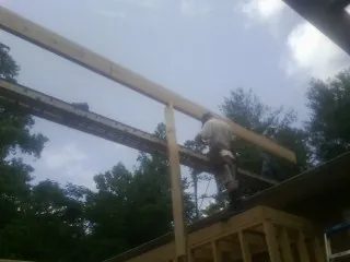 Carpenter setting a ridge beam over a new addition frame — Ice Dam Removal by Roofing Brothers in Clarks Grove