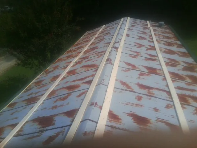 Rusted metal roof panels with new wood purlins before replacement — Storm Damage Roof Repair in Clarks Grove by Roofing Brothers
