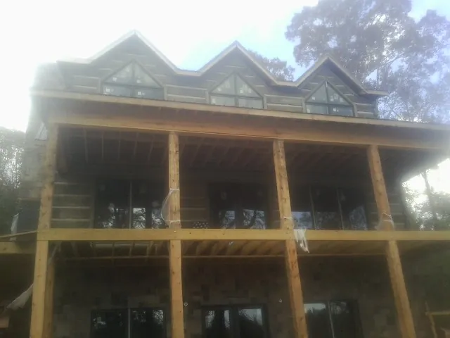 Dormers and porch framing on a large log home under construction — Roof Coating work by our crew in Clarks Grove