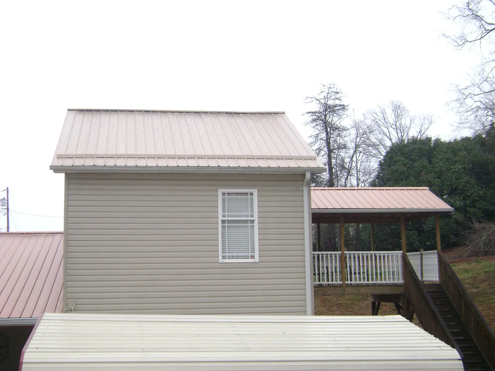 Tan metal roofs on a two story addition and attached porch in Clarks Grove