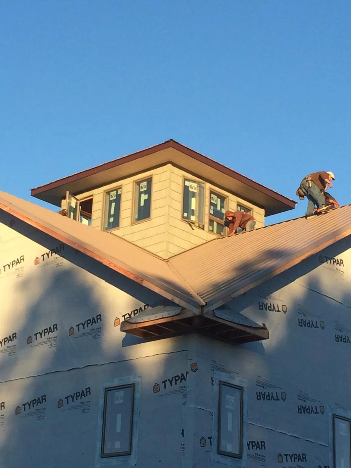 Roofers working around a rooftop cupola on a new metal roof at sunset — Roof Waterproofing in Clarks Grove by Roofing Brothers